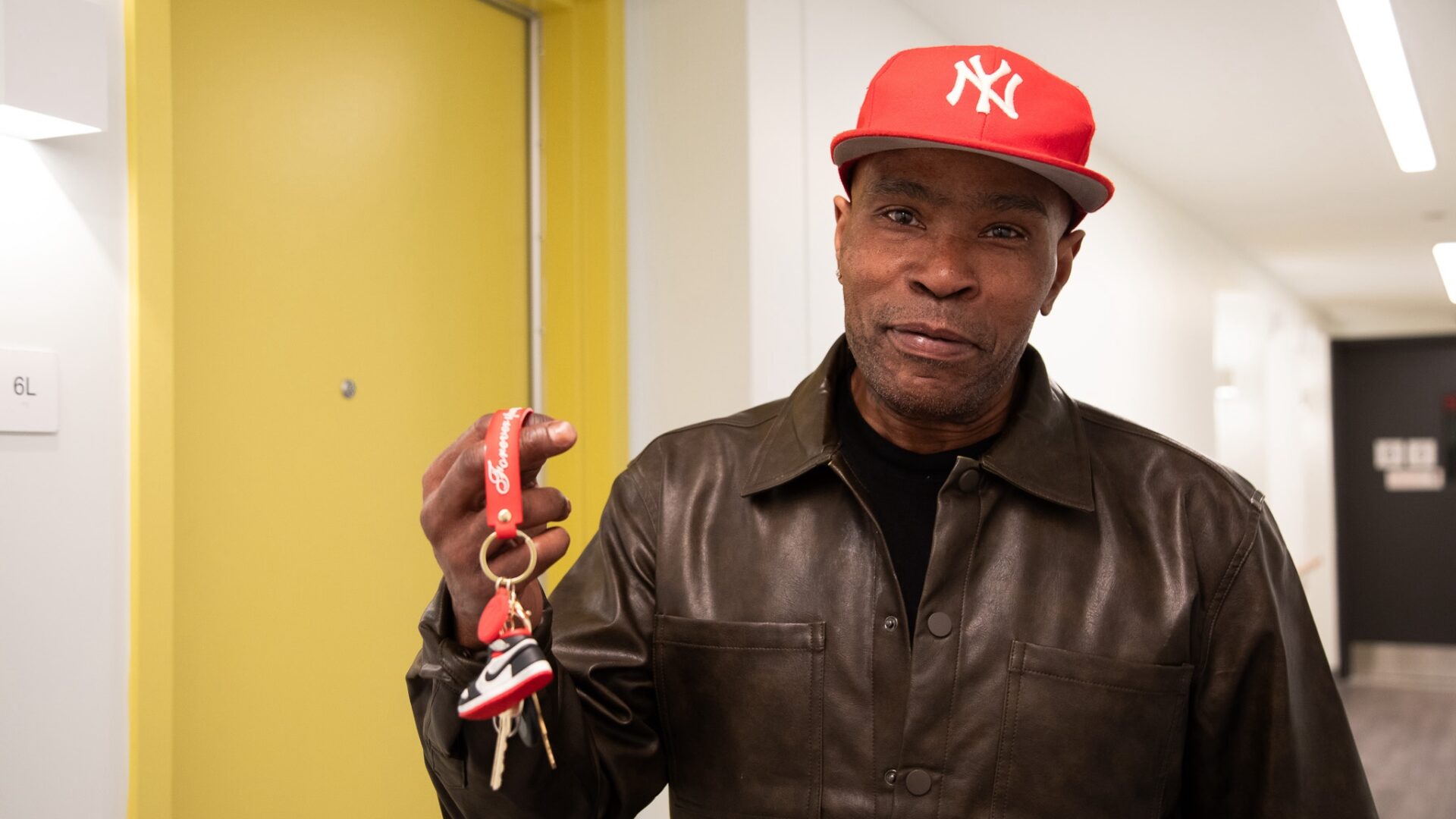 A man in a red Yankees cap holding a set of keys