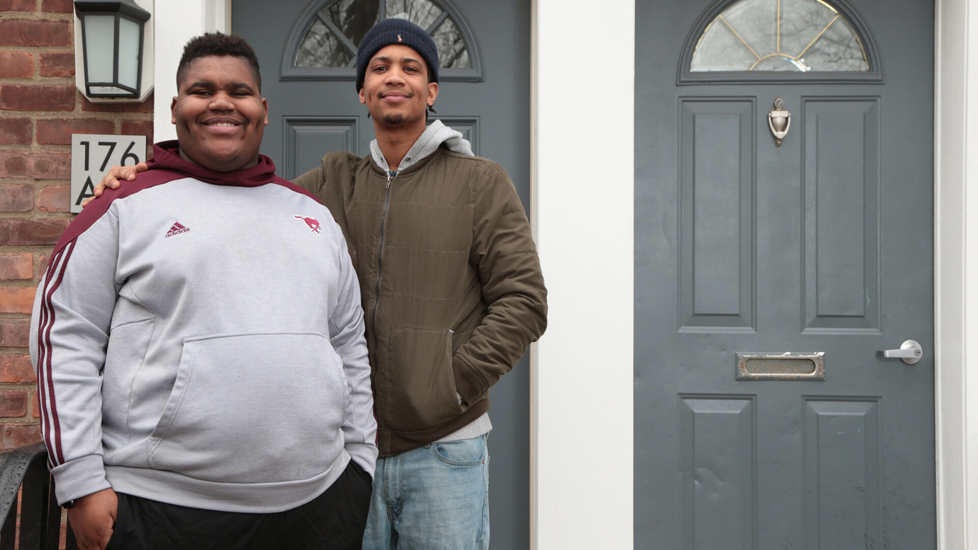 Two young men in front of a residence