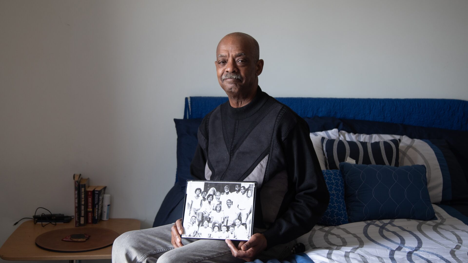 An older man holding a black and white group photo