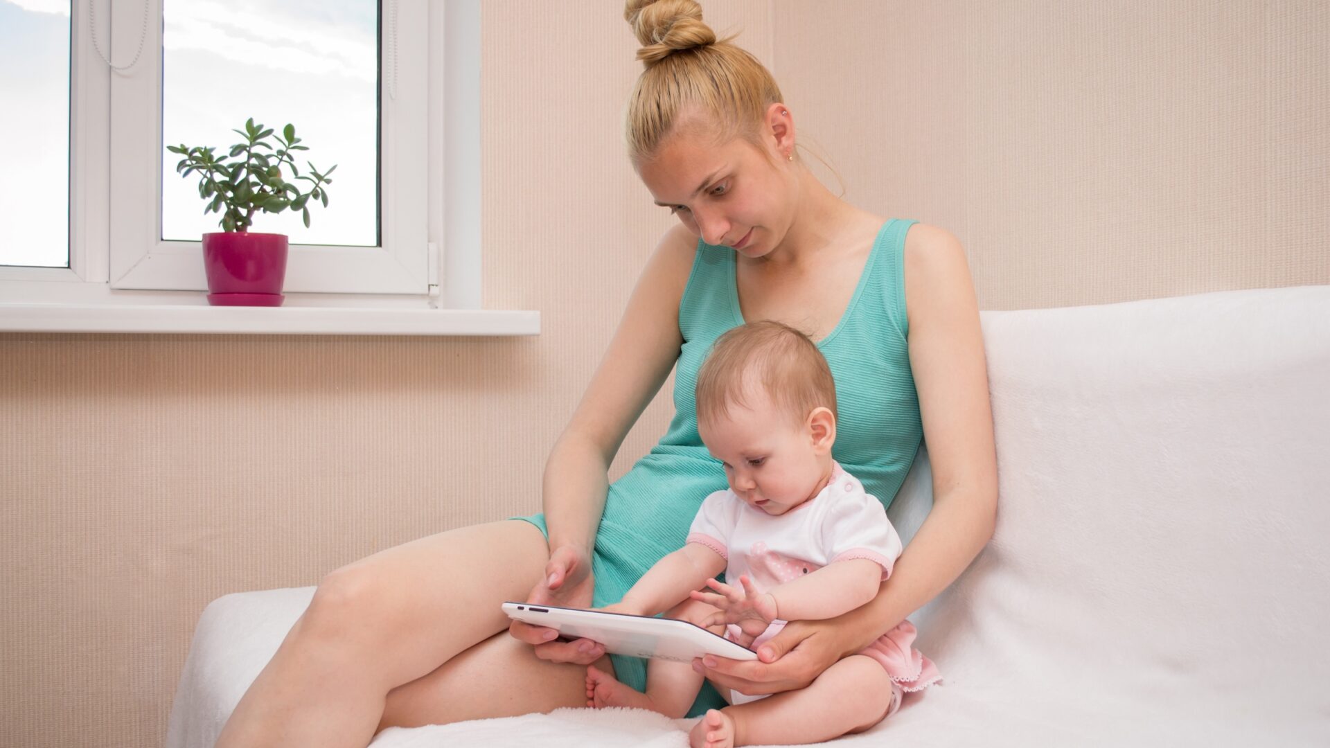 A young woman showing a tablet device to a baby