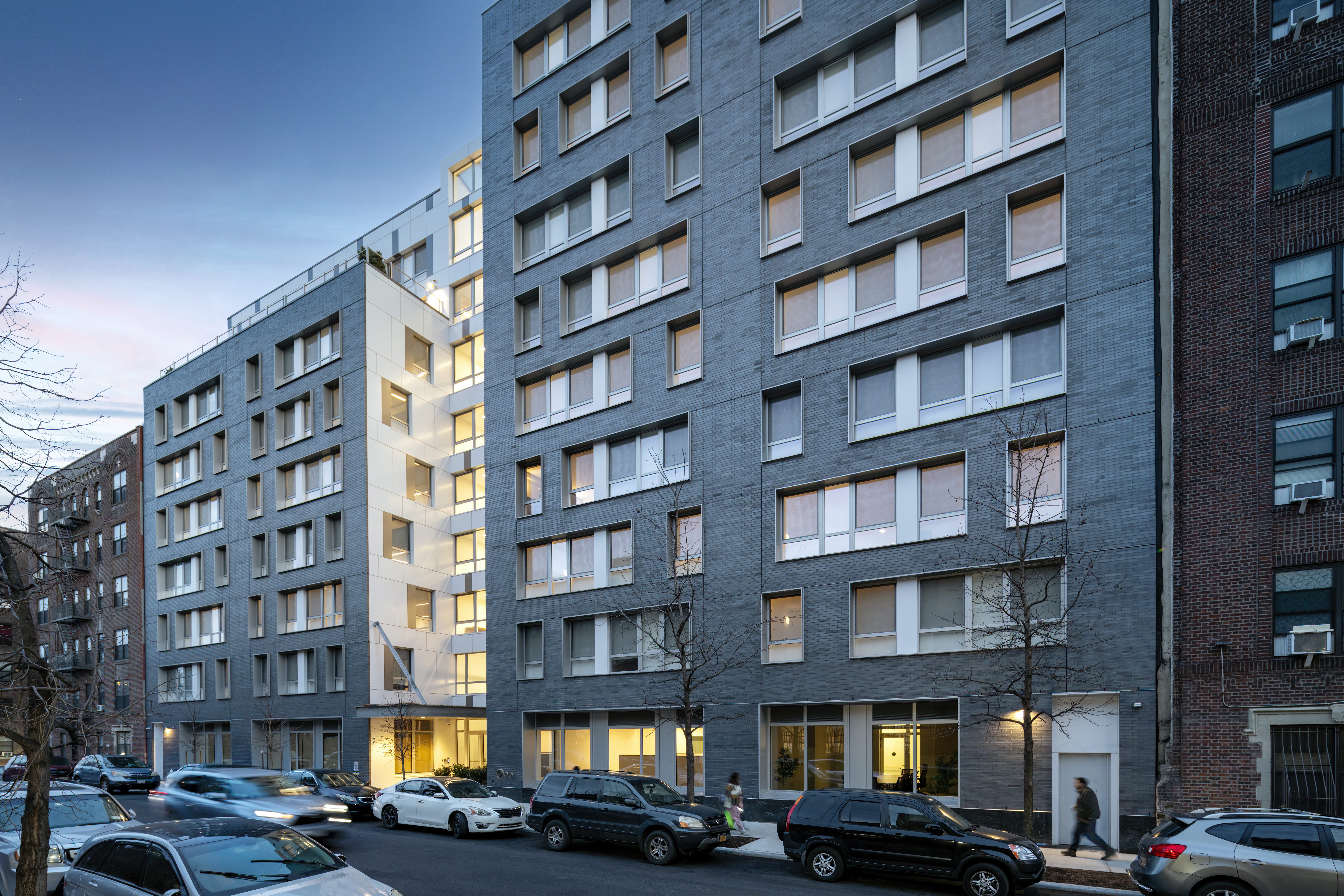 A tall building with cars parked on the street.