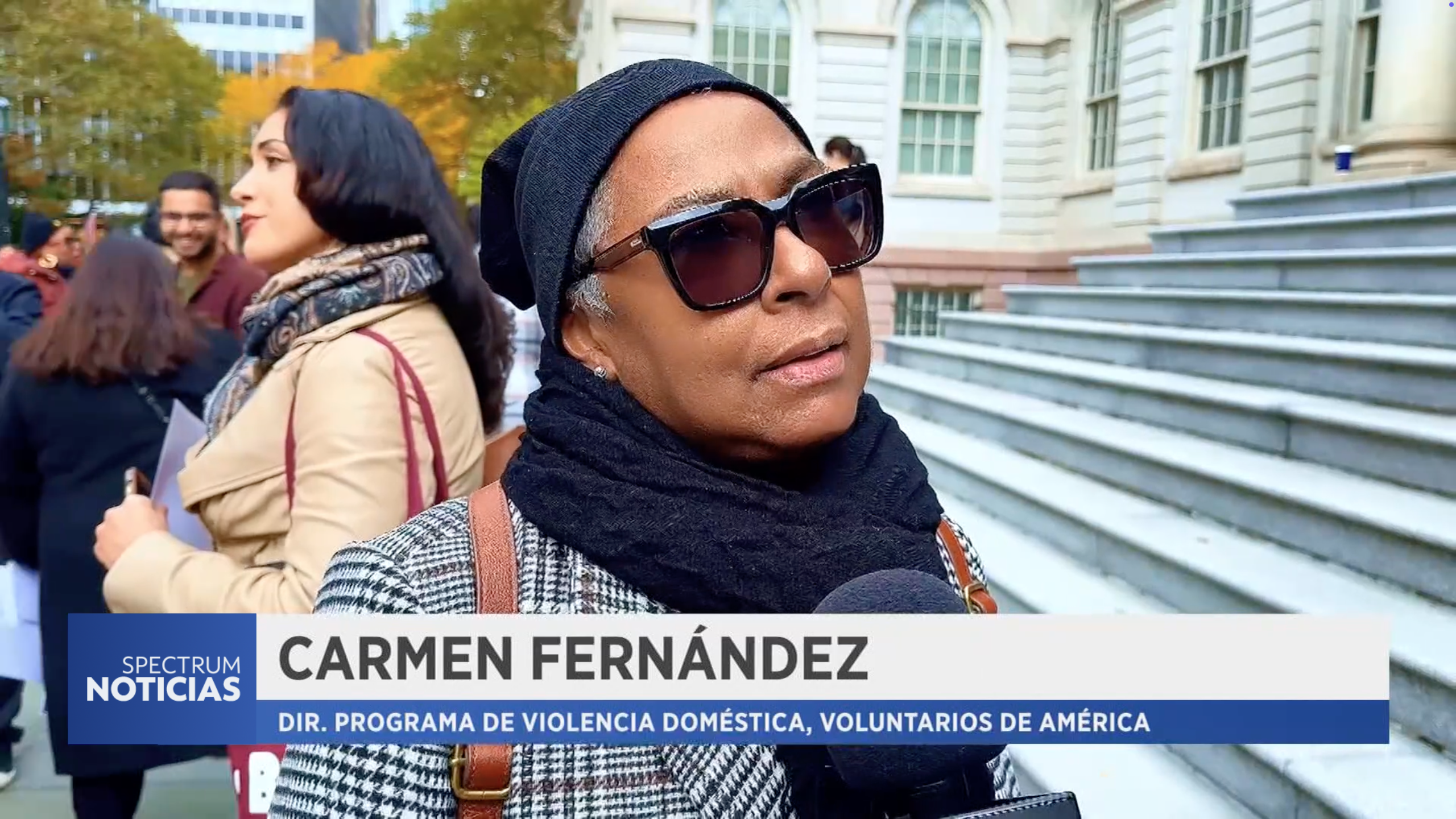 A screenshot of a Spectrum NY1 newscast of a woman being interviewed in front of the city hall steps.
