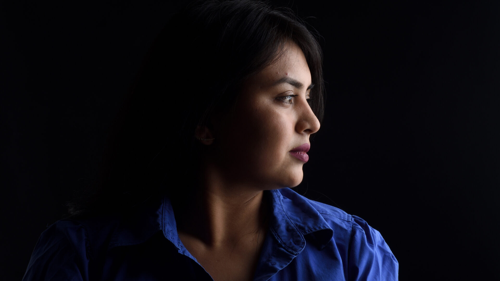 Portrait of a woman looking to the right against a black background.