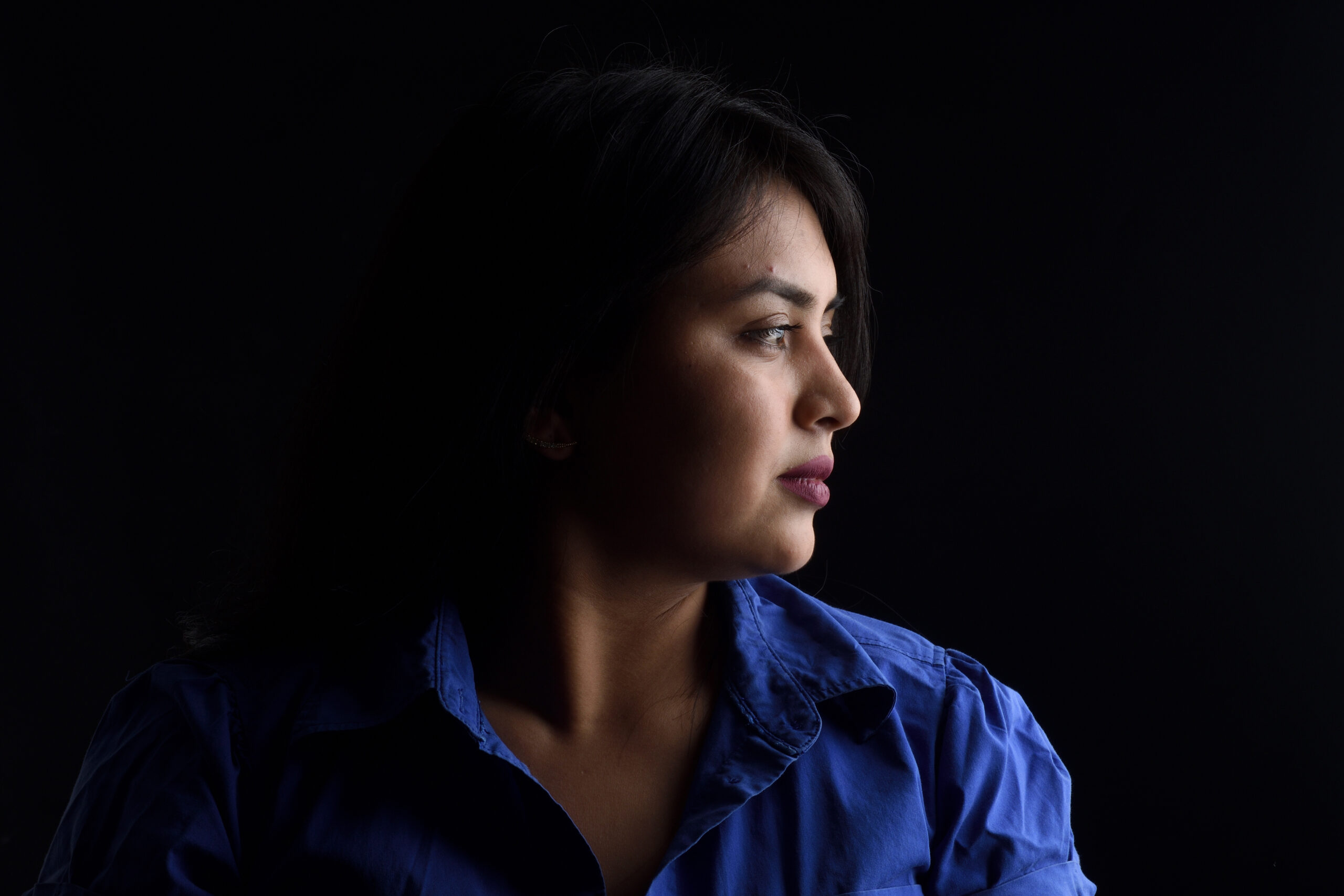 Portrait of a woman looking to the right against a black background.