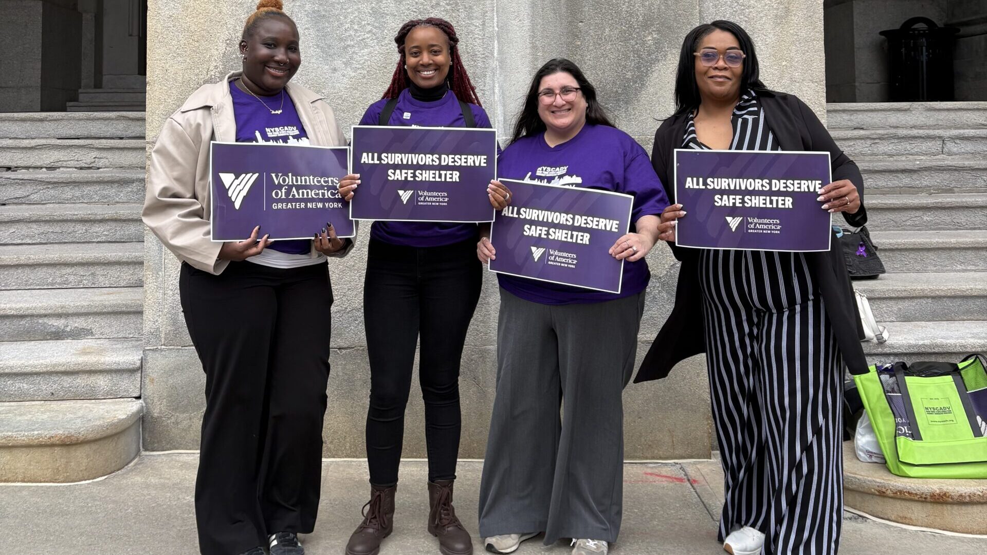 VOA-GNY staff stand outside New York State capitol holding signs reading "All survivors deserve safe shelter"