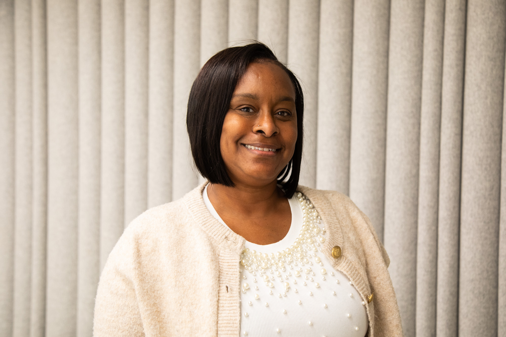 Leslie Armstrong smiles for the camera, wearing a white top and beige sweater.